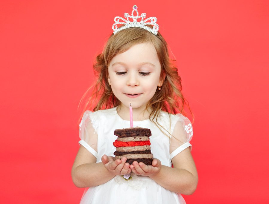 A little girl holding a cake with candles in it.