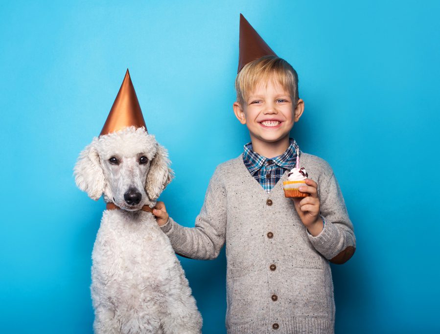 A boy and his dog wearing party hats.