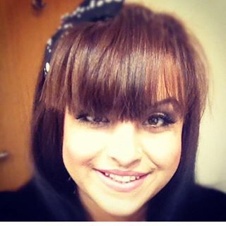 A woman with brown hair and bangs smiling for the camera.