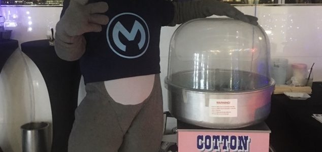 A person in costume next to a cotton candy machine.