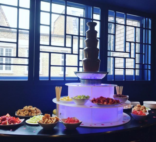 A large chocolate fountain with many different foods on it.