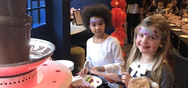 Two girls standing in front of a chocolate fountain.