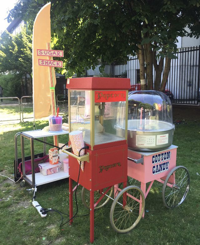 A red and white cart with a popcorn machine on it