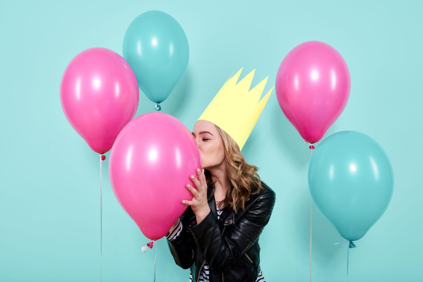 A woman wearing a crown and holding balloons