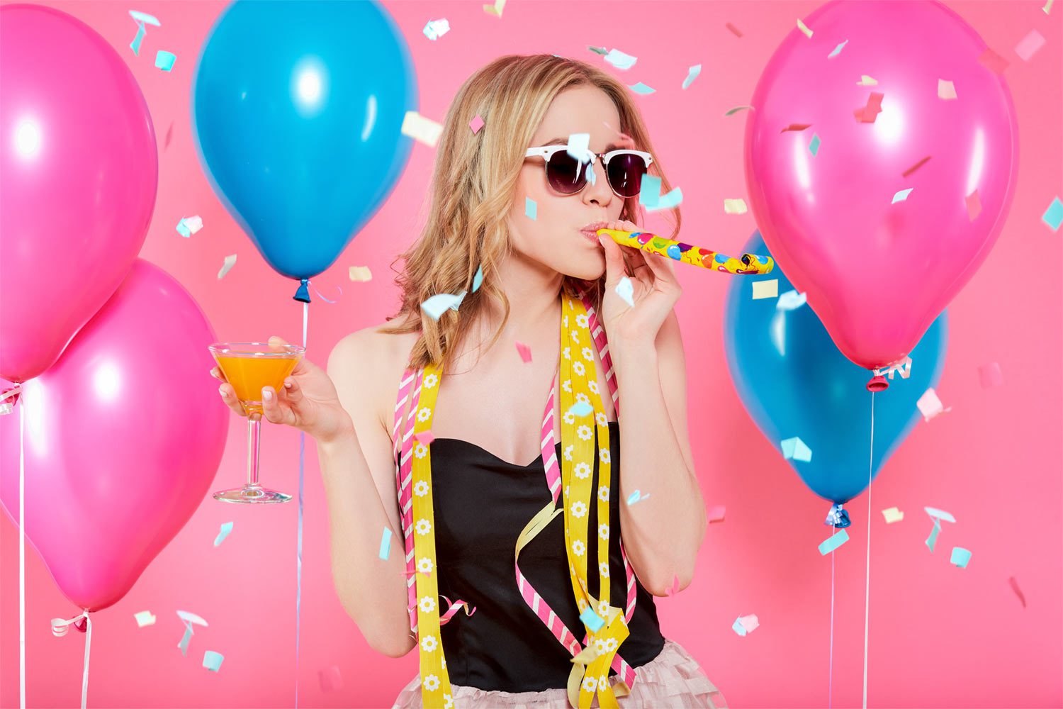 A woman with pink balloons and drinking straws.