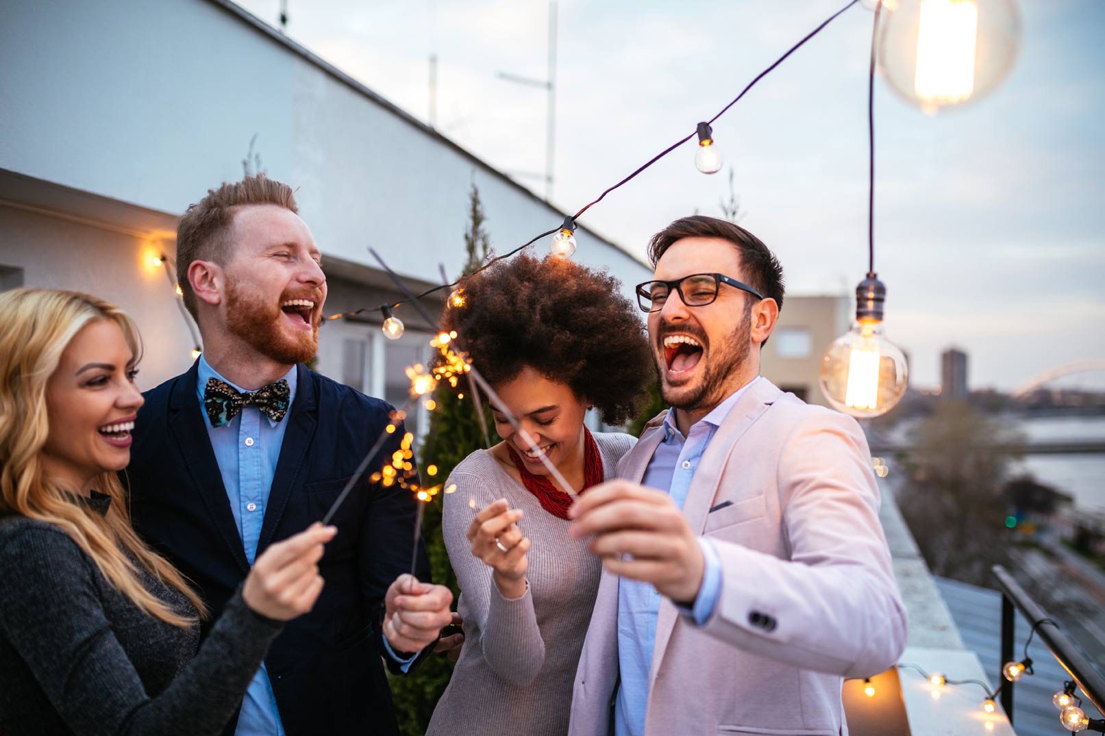 Three people are laughing together outside at night.