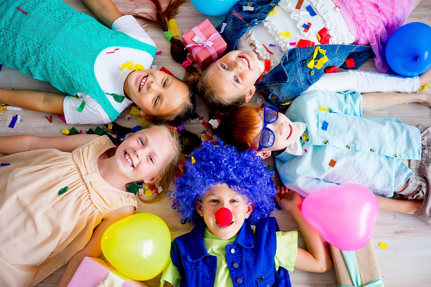 A group of children laying on the ground with balloons