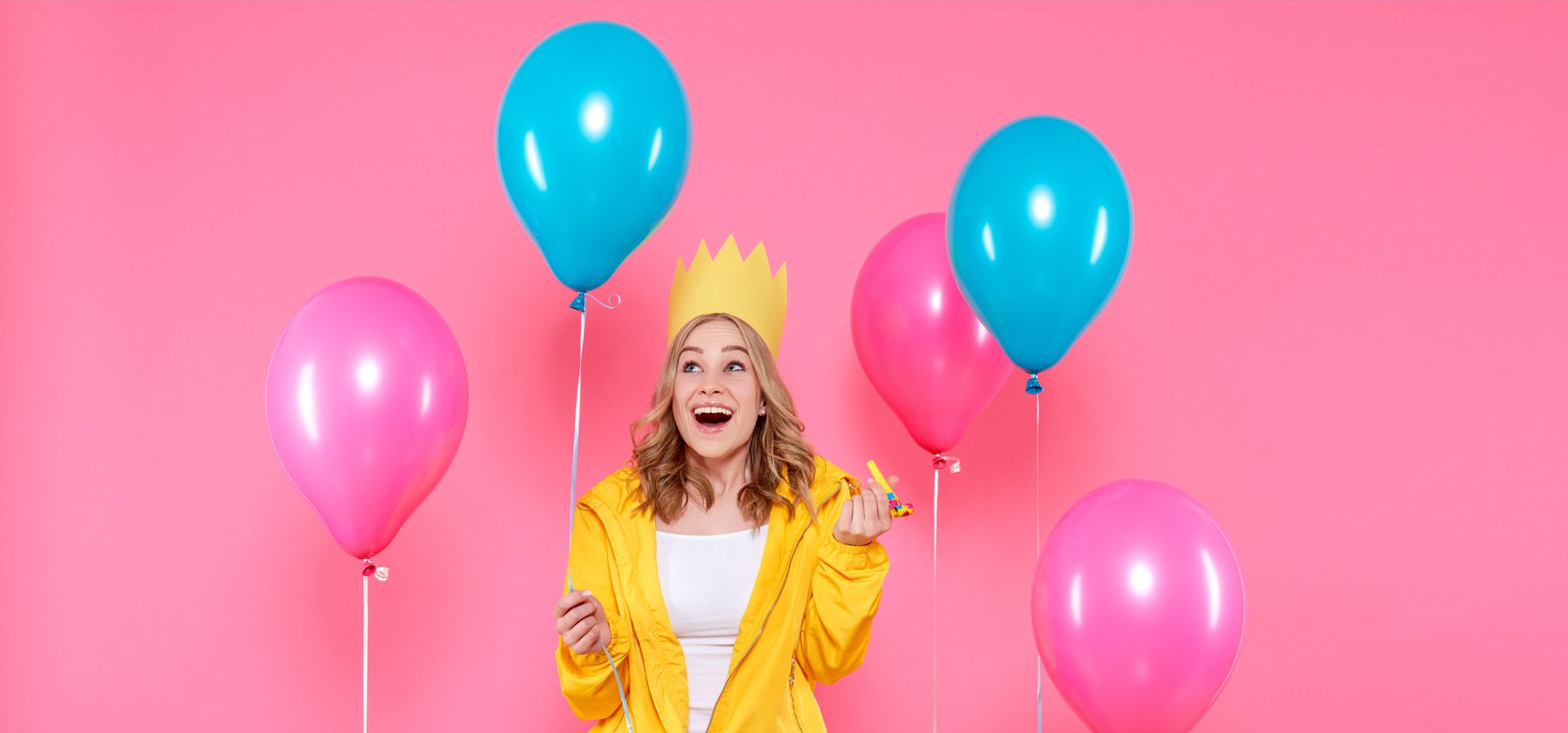 A woman wearing a crown and holding two balloons.