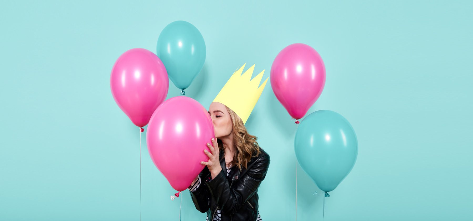 A woman wearing a crown and holding balloons