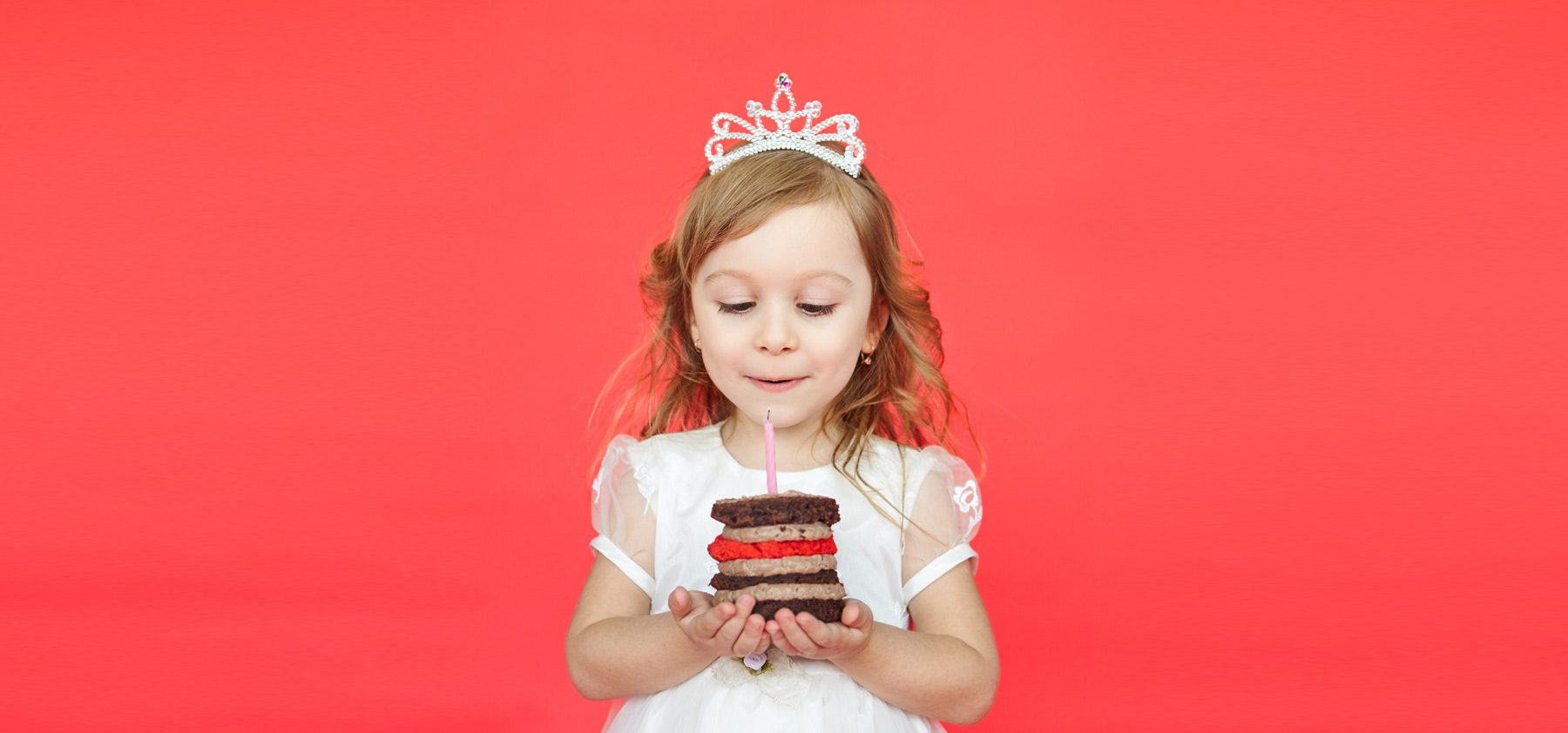 A little girl holding a piece of cake in her hands.