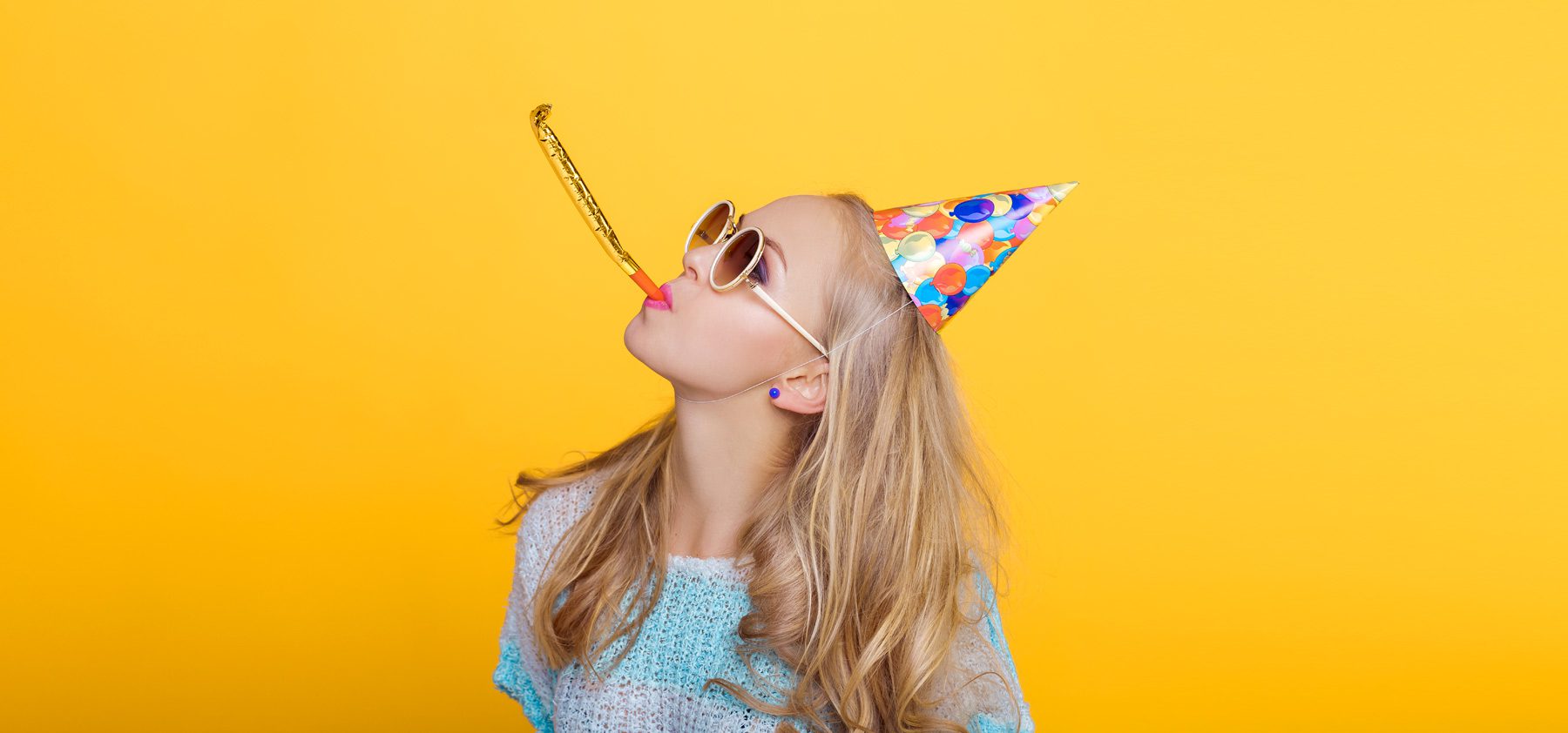 A woman wearing sunglasses and a party hat.