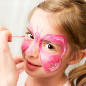 A little girl with pink butterfly face paint.