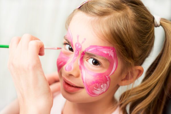 A little girl with pink butterfly face paint.