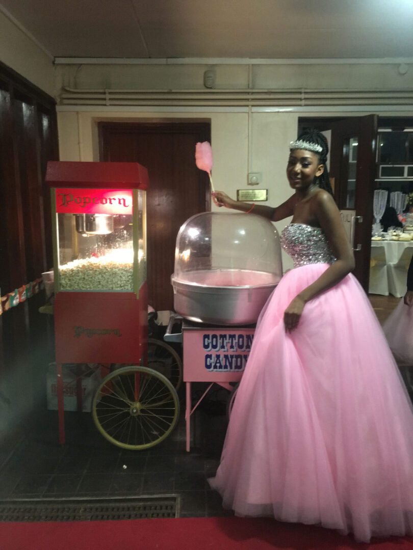 A woman in a pink dress standing next to a candy cart.