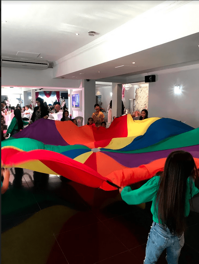 A group of people holding large rainbow colored umbrellas.